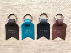Leather keyring from Bookshell Bindery shown here in all available colours and phrases – Dark brown, blue, black, light brown