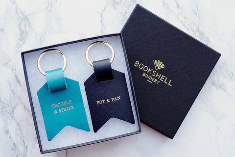 Couple keychain from Bookshell Bindery in turquoise blue leather and black leather, Trouble and strife (wife), Pot and pan (Old man)